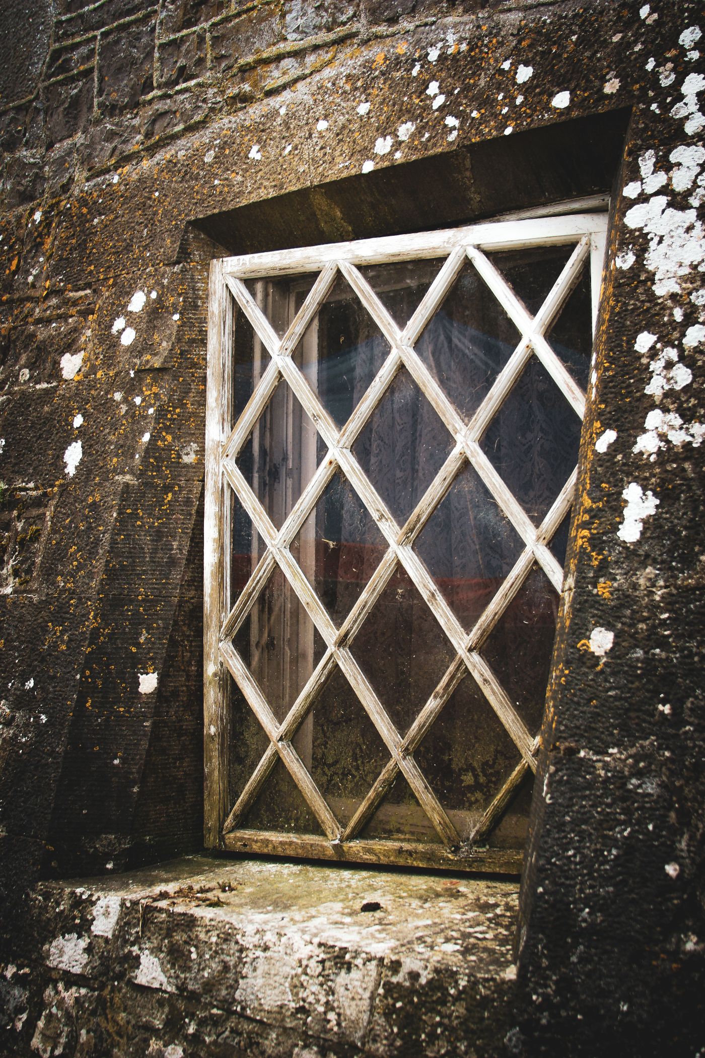 A lattice window set into a weathered stone wall, a thematic image for Cersei’s restricted view.