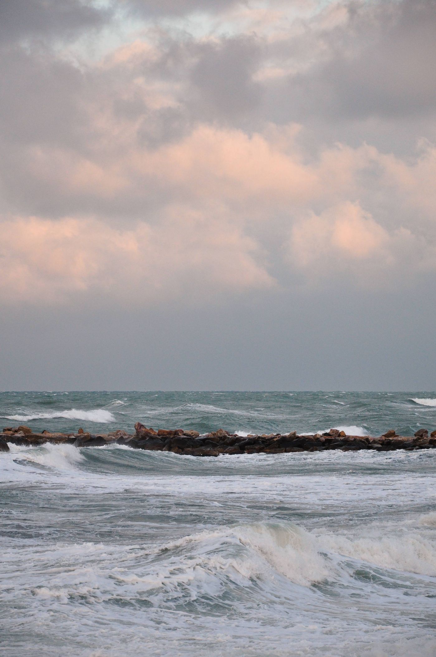 Waves breaking against a rocky coast beneath cloudy skies, a thematic photograph of sea power.